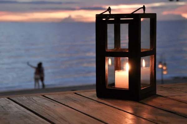 Linterna de vela con pareja en la playa como fondo —  Fotos de Stock
