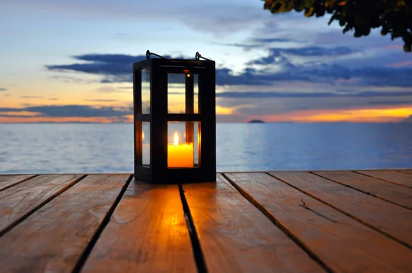 Kaars lantaarn op houten tafel met twilight zee achtergrond — Stockfoto