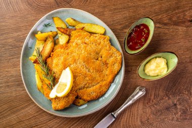 Mavi tabakta kızarmış patatesli şnitzel. 