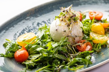 Mozzarella topu ve mavi tabakta sebze salatası.