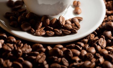 Bir fincan tabağında espresso kahvesi ve kahve taneleri olan bir dama. 