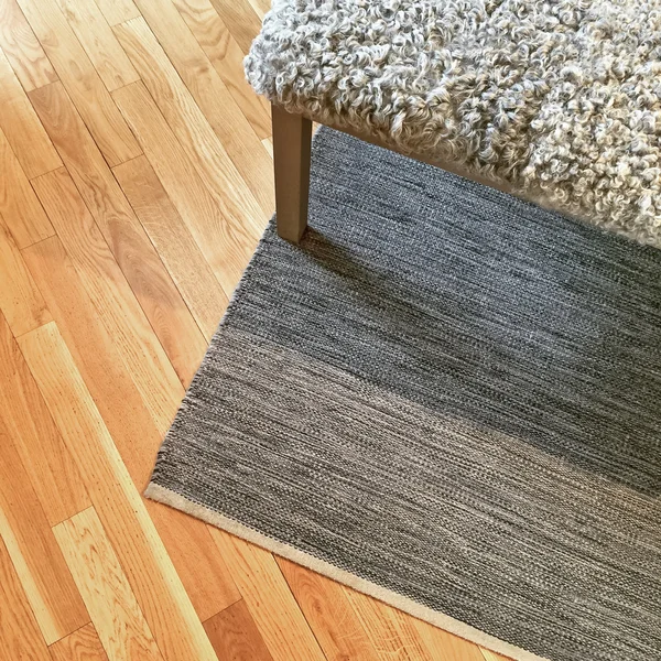 Ovčí kůže lavice na dřevěnou podlahu — Stock fotografie