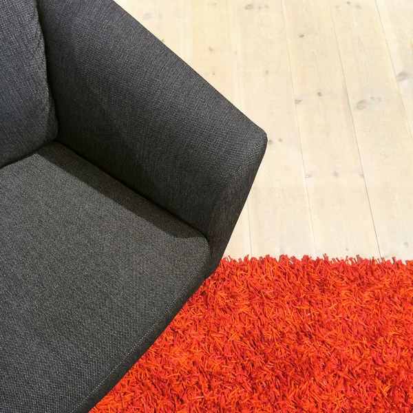 Sillón textil gris sobre alfombra roja —  Fotos de Stock