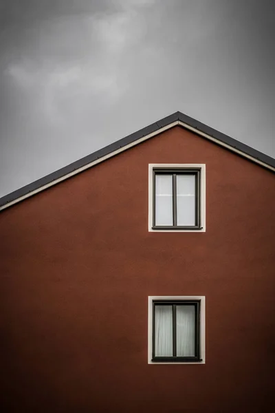 Красный Дом Белыми Окнами Фоне Тёмного Облачного Неба — стоковое фото