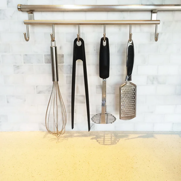 Kitchen utensils on a metal wall rail — Stock Photo, Image