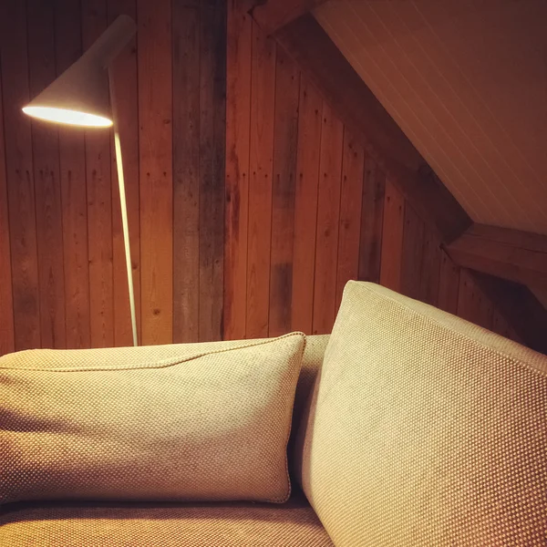 Sofá e lâmpada em uma sala com paredes de madeira — Fotografia de Stock