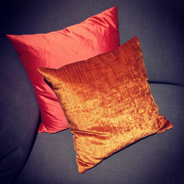 Almofadas vermelhas e laranja brilhantes decorando um sofá — Fotografia de Stock