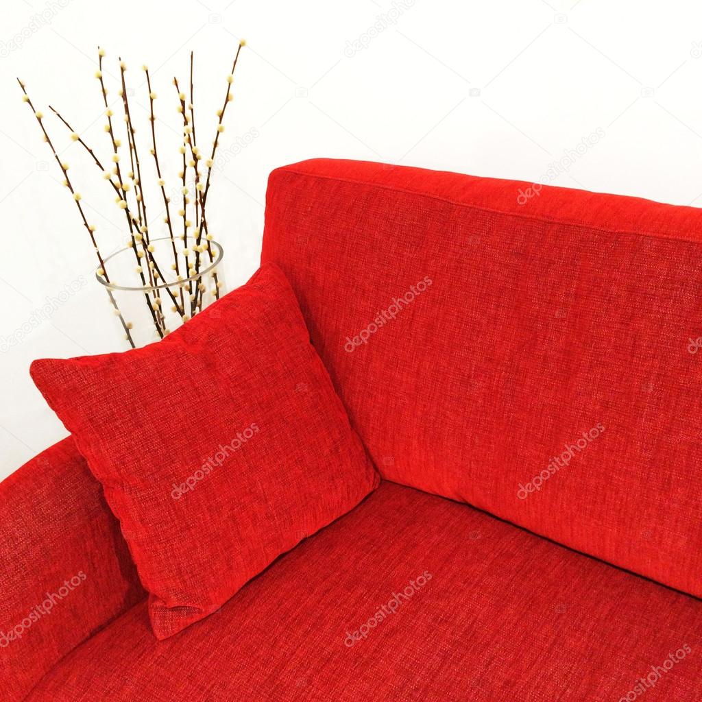 Red velvet sofa and willow branches in a vase