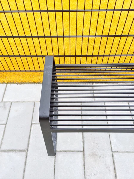 Heldere gele speeltuin en metalen bankje — Stockfoto