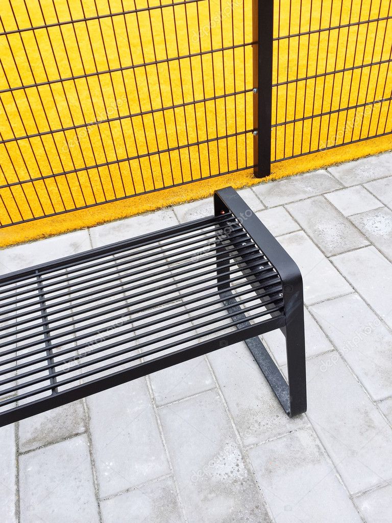 Metal bench near bright yellow playground