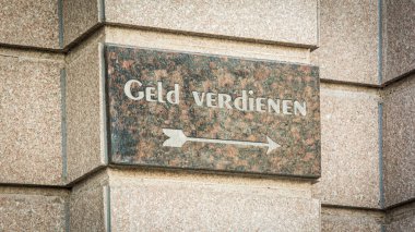 Fotoğraf bir tabela ve Almanca para kazanma yönünü gösteren bir tabela gösteriyor..