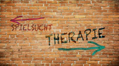 Almanca 'nın iki farklı yönünü gösteren işaret direği olan bir resim. Bir yön kumar bağımlılığını, diğer yön terapiyi işaret ediyor..