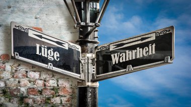 Almanca 'nın iki farklı yönünü gösteren işaret direği olan bir resim. Bir yön gerçeği gösterir, diğeri yalanı..