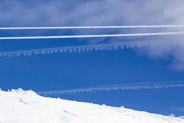 两条平行的绳索被冰雪覆盖在蓝天的背景上 云彩形成了线条 蓝白相间的背景 复制空间 — 图库照片