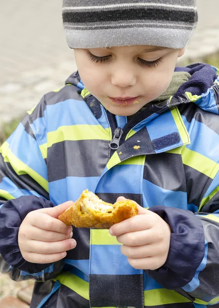 Child eating snack on street — Stock Photo, Image