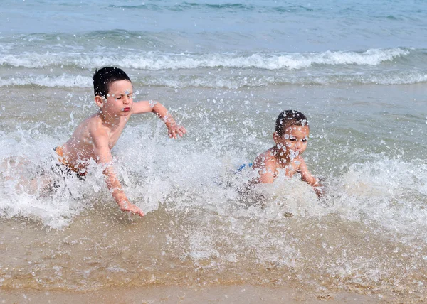 Dzieci bawiące się w fale Morza — Zdjęcie stockowe