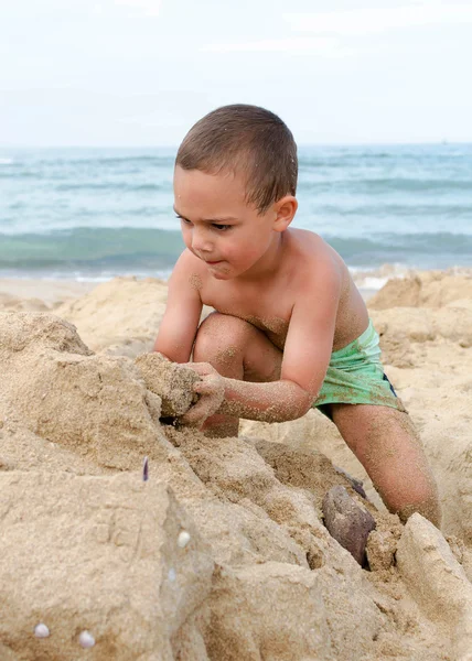 Criança brincando com areia na praia — Fotografia de Stock