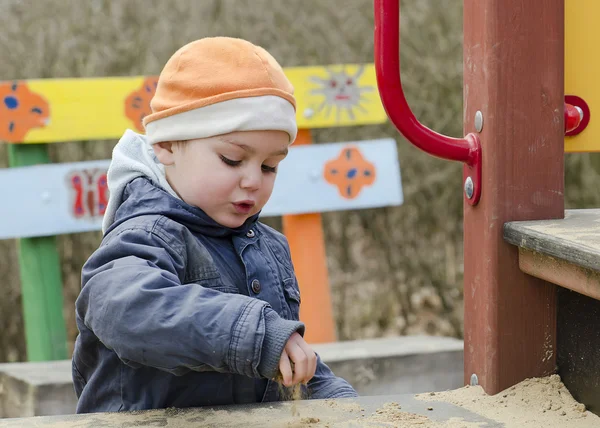 Kind auf Spielplatz spielt mit Sand — Stockfoto