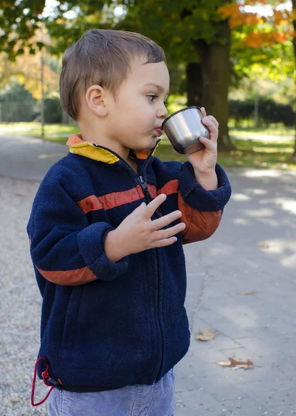 Child drinking tea in park — Stock Photo, Image