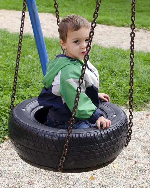 Niño en columpio en el parque infantil — Foto de Stock