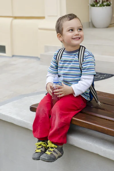 Dítě na lavici s lahví vody — Stock fotografie