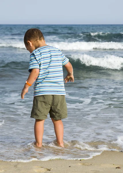 Niño de pie en la playa en el agua . — Foto de Stock