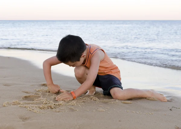 Barn leker med sand på stranden — Stockfoto