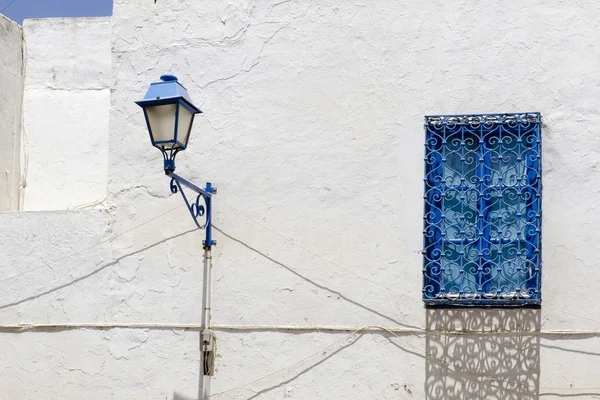 Синее окно и лампа на доме в Тунисе — стоковое фото