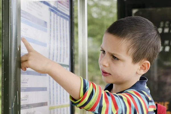 Child  reading timetable at  bus stop — Stock Photo, Image