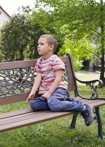 Kind sitzt auf Bank — Stockfoto