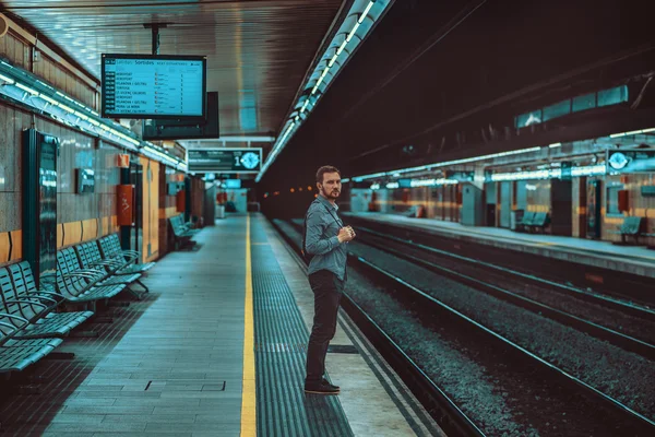 man standing on the platform waiting for the subway and train