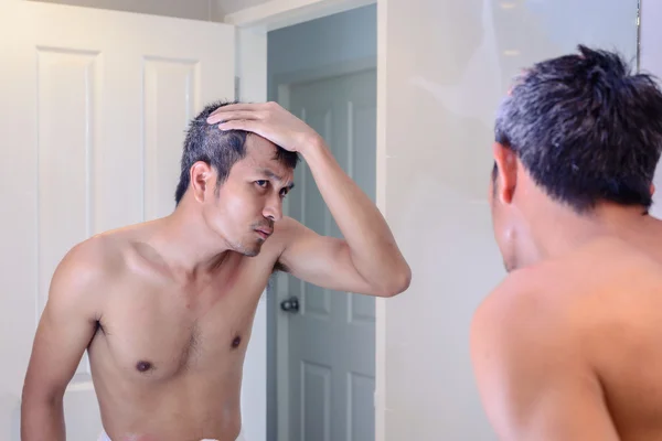 Homem preocupado com cabelos grisalhos enquanto olha para um espelho . — Fotografia de Stock