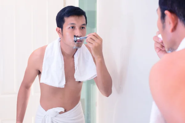 Jovem bonito homem barbear por si mesmo com espelho . — Fotografia de Stock