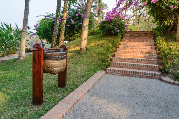 Uso de cesta de bambú para mantener la basura cerca del sendero en el jardín . —  Fotos de Stock
