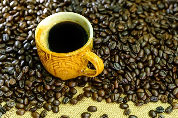 Hot americano, Black coffee in yellow cup with coffee beans on s — Stock Photo, Image