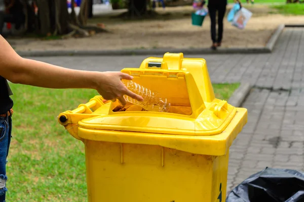 Χέρι που ρίχνουν το μπουκάλι στο κίτρινο κάδο απορριμάτων. — Φωτογραφία Αρχείου
