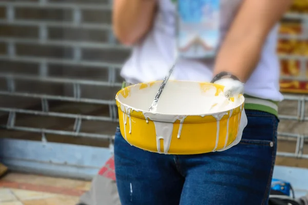 White color in yellow bucket for paint wall with paint roller.