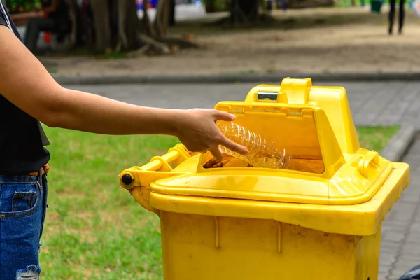 Χέρι που ρίχνουν το μπουκάλι στο κίτρινο κάδο απορριμάτων. — Φωτογραφία Αρχείου