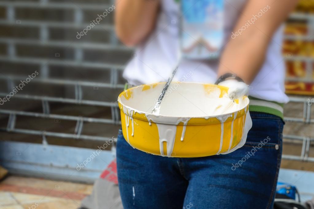 White color in yellow bucket for paint wall with paint roller. Stock
