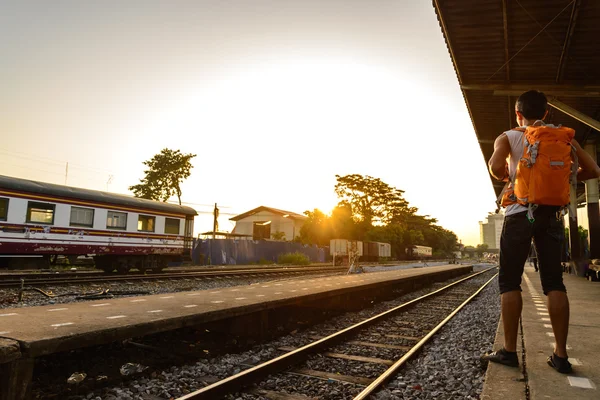 Backpacker with orange bag waiting a train at platform. — Stock Photo, Image