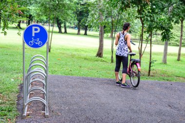 Bisiklet yamaçta alanda kadın ve kırmızı bisiklet ile tabelada Park.