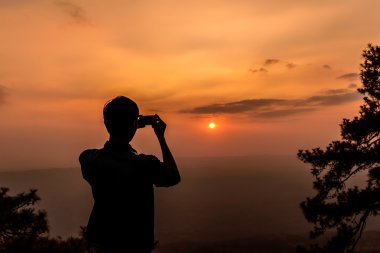 Günbatımı ile smartphone bir fotoğraf çekici adamın Shilouette.