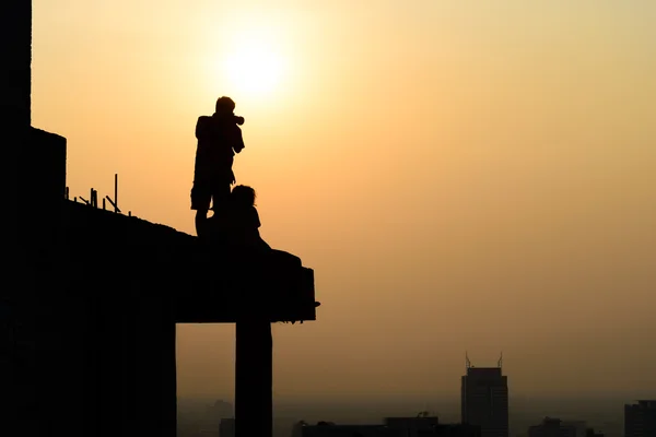 Silhouetted of photographer shooting cityscape at building roof. — Stock Photo, Image