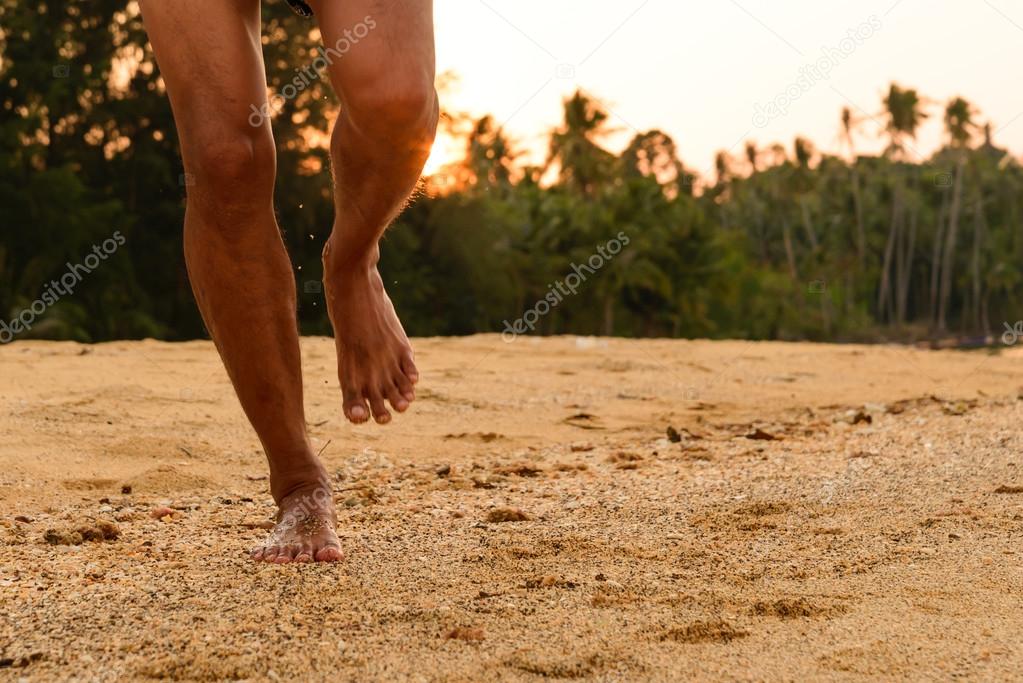 Barefoot running on beach at sunset.