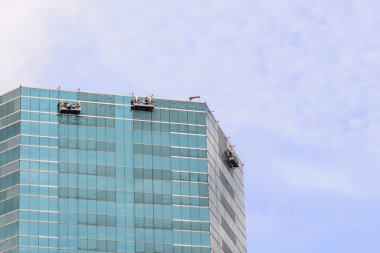 Yüksek binadaki pencereleri temizleyen bir grup işçi.