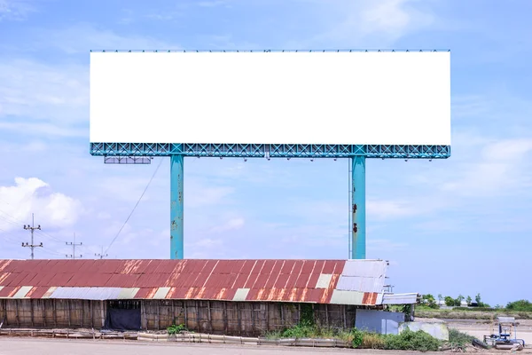 空白广告牌背后的盐棚锈迹斑斑的屋顶与蓝天广告. — 图库照片