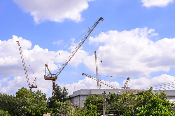 Gebouw in aanbouw en kranen tegen blauwe hemel. — Stockfoto