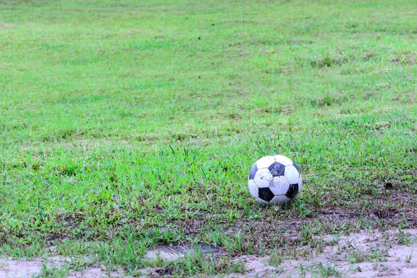 Bola de futebol suja no campo molhado . — Fotografia de Stock