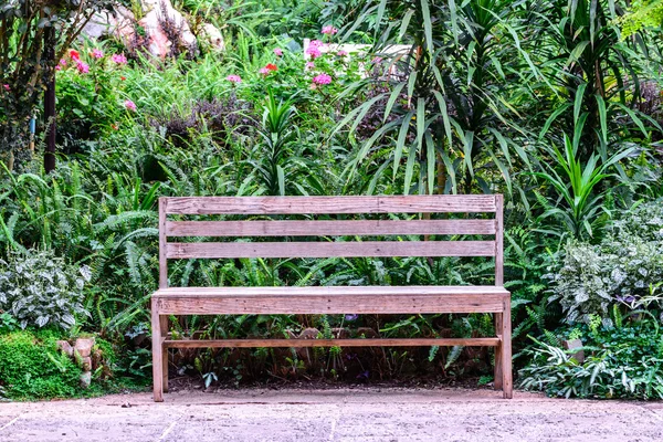 Drewniana ławka wśród kwiatów ogród. — Zdjęcie stockowe
