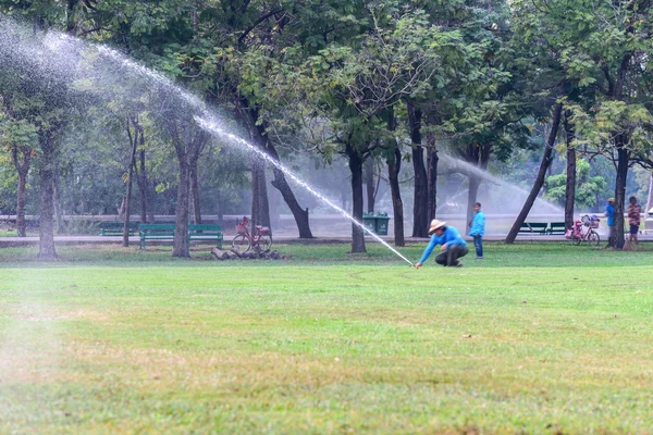 Tuinman water gazon met behulp van water sprinklerinstallatie. — Stockfoto